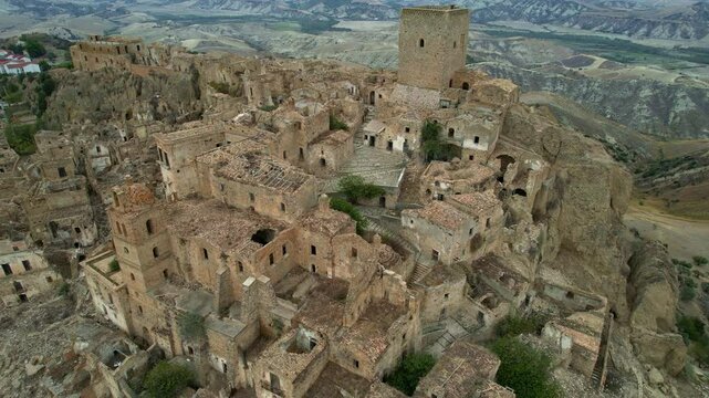 4K Aerial drone video of mystical ghost town on top of the hill with ruins and empty houses. Haunted village with crumbling structures and fallen church. Abandoned city Craco, Matera, Italy