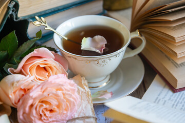 Beautiful roses, a cup of tea and many books on the table