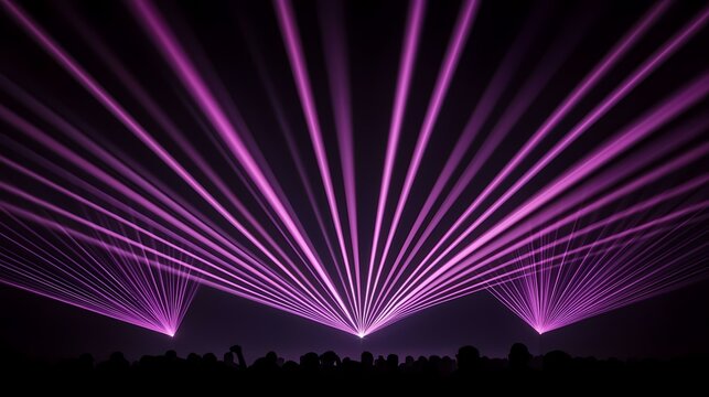 The image shows a crowd silhouetted in front of three purple lasers, creating a dramatic and vibrant scene.