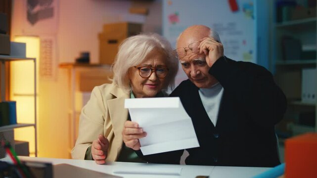 Senior entrepreneurs reading a letter about winning a business grant, success