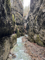 The beautiful stream flows through the rocky valley of Partnachklamm Gorge, where lush moss clings to stones, creating a vibrant and serene natural scene in Garmisch-Partenkirchen.