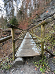 A rustic wooden bridge spans the trail leading up to Kaiserschmarrn-Alm, offering hikers a charming path through the scenic beauty of Partnachklamm Gorge in Garmisch-Partenkirchen.