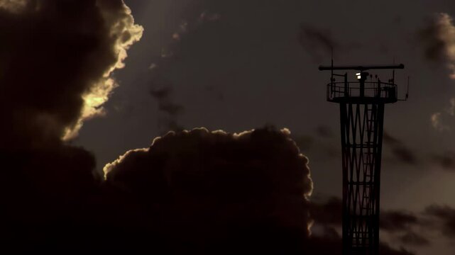 Air Navigation System and the Gathering Storm. Communication tower with a rotating antenna and flashing signal lights against the background of rapidly changing weather at dusk