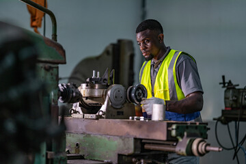 A focused technician operates heavy machinery in an industrial workshop. Dressed in a high-visibility vest, he exemplifies concentration and skill in a metalworking environment, ensuring precision.