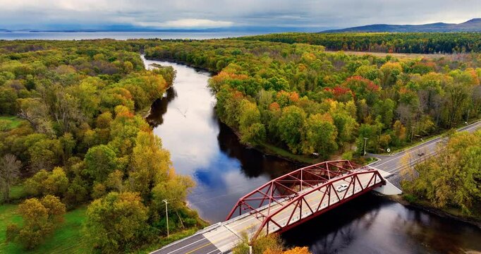 Aerial view of the iron bridge over the Ausable river. Autumn landscape with yellow trees on the background of the lake Champlain and hills.