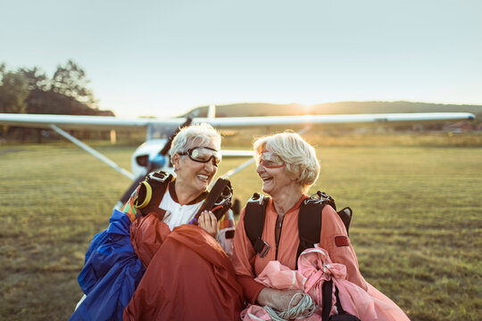 Two senior women laughing after skydiving adventure at sunset