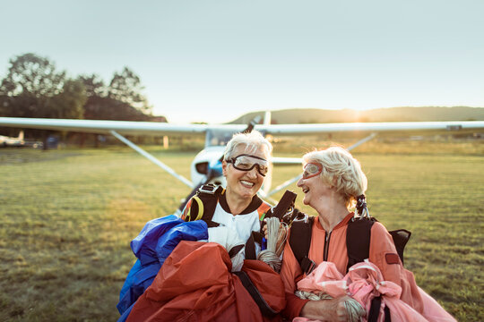 Two senior women laughing after skydiving adventure at sunset