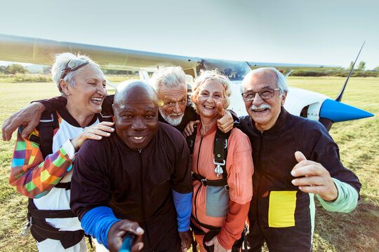 Diverse senior friends taking group photo after skydiving