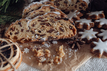 A festive plate featuring traditional German Christmas treats, including slices of Stollen bread filled with dried fruits and nuts, accompanied by star-shaped cinnamon cookies glazed with white icing.