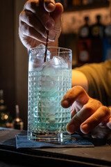 Professional bartender stirring craft cocktail with ice in crystal glass, mixology and modern bartending