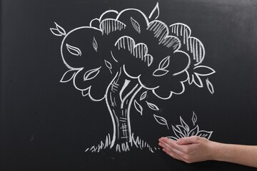 Woman pretending to catch leaves fallen from tree on chalkboard, closeup