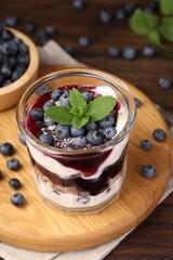 Tasty trifle dessert. Blueberries, sponge cake and whipped cream in glass on wooden table