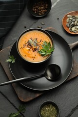 Delicious pumpkin soup with spices served on dark textured table, flat lay