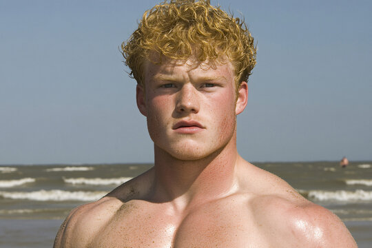 handsome redhead man on the beach with freckles and sand on his skin