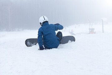Person with snowboard on the snow. boy falling with snowboard at winter. Winter sport.