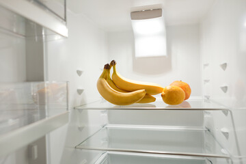 bunch of ripe bananas in empty refrigerator. bananas at empty refrigerator. open refrigerator door.