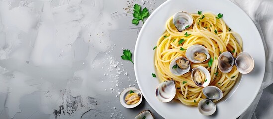 Traditional Italian seafood pasta featuring clams and parsley Spaghetti alle Vongole served in white plates against a grey background top view. with copy space image. Place for adding text or design