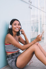 Happy female millennial in earphones enjoying leisure time for listening cellular music playlist...