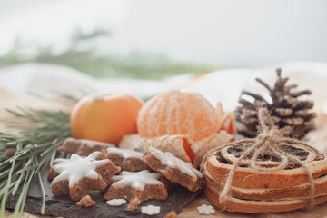 Tangerines and German Christmas pastries, chocolate gingerbread and star-shaped cookies with white icing.Traditional Christmas stollen made of dried fruits and nuts sprinkled with powdered sugar on t
