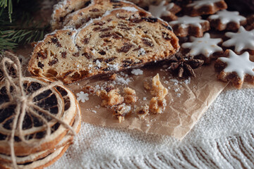 Tangerines and German Christmas pastries, chocolate gingerbread and star-shaped cookies with white icing.Traditional Christmas stollen made of dried fruits and nuts sprinkled with powdered sugar on t
