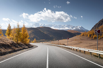highland road. autumn highway in front of ice peaks.