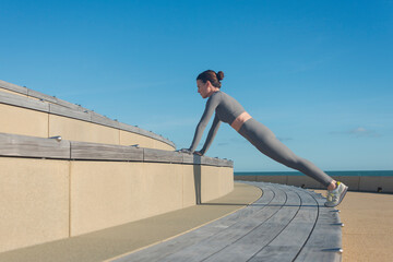 sporty woman doing a plank, push up exercise on a bench