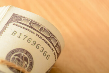 A stack of US dollar bills is neatly bundled and tied with a string.