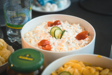 White bowl with white cabbage salad, garnished with tomatoes and cucumber