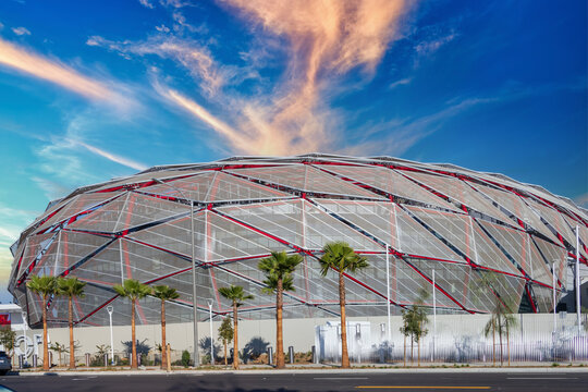 the Intuit Dome with lush green palm trees and powerful clouds at sunset in Inglewood California USA