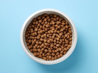 Fototapeta premium Pet food bowl filled with dry kibble against a light blue background, showcasing a healthy meal option for furry companions