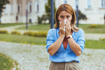 Woman Experiencing Allergies Sneezing Outdoors in Park Setting