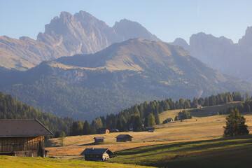 Idyllic view of Alpe di Siusi in the Italian Dolomites, South Tyrol, with rustic cabins on alpine meadows surrounded by majestic mountain peaks.
