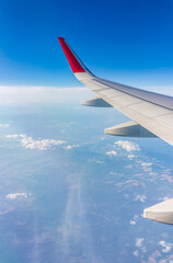 Fototapeta premium View from the airplane window at a beautiful cloudy sky and the airplane wing
