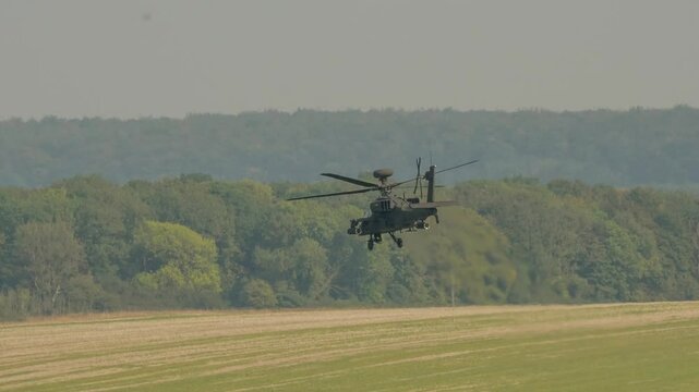 British army Boeing Apache Attack helicopter gunship AH2 AH64E AH-64E AAC in low-level flight over a grass meadow, Wilts UK