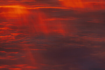 A vibrant, fiery sky with rich red and orange clouds, capturing the dramatic beauty of a sunset. The gradient of colors creates a warm, atmospheric scene.