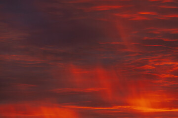 A vibrant, fiery sky with rich red and orange clouds, capturing the dramatic beauty of a sunset. The gradient of colors creates a warm, atmospheric scene.