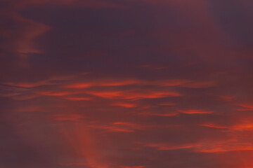 Obraz premium A vibrant, fiery sky with rich red and orange clouds, capturing the dramatic beauty of a sunset. The gradient of colors creates a warm, atmospheric scene.