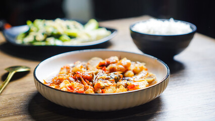 A white bowl of food sits on a wooden table