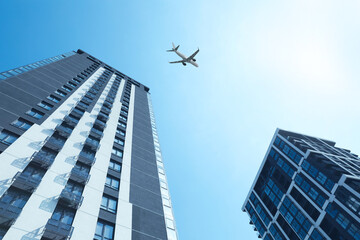 Fototapeta premium Airplane flying over buildings in city, low angle view