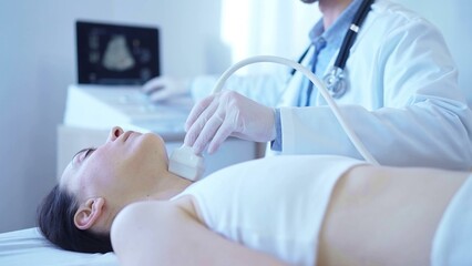 Doctor man with white medical gloves is using ultrasound machine to examine neck of female patient lying down in clinic. Medicine concept