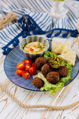 Falafel plate with hummus, cherry tomatoes, lettuce, and pita chips, perfect Mediterranean meal