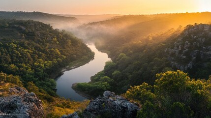 A winding river flows through a valley shrouded in mist at sunrise.