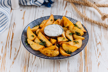 Golden potato wedges with herbs and creamy dip, perfect for any meal or snack