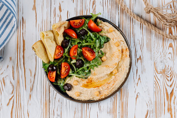 Mediterranean hummus plate with fresh vegetables, olives, and pita bread for a perfect meal