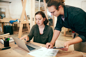 Carpentry, planning and people on laptop in workshop for timber, lumber and furniture manufacturing. Construction business, woodworking and man and woman on tech for online order, teamwork or meeting