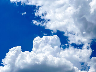 Bright white clouds float across a vibrant blue sky on a sunny day, evoking a sense of calm and...