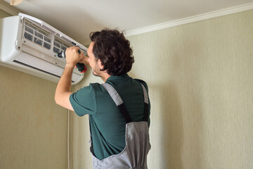A Skilled Professional Worker is Installing a Ceiling Appliance Using a Power Drill Tool