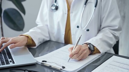 Doctor woman is working on laptop with medical reports. Healthcare professional reviews patient files and inputs data in a clinic setting. Medicine