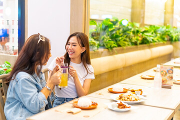 Family relationship, mother's day concept. Happy Asian mother and daughter enjoy outdoor lifestyle shopping and having lunch eating food together in restaurant at shopping mall on holiday vacation.