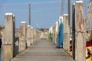 Obraz premium Wooden bridge pier in harbor on Terschelling island, Sidewalk way by haven or quay shore, The Dutch Wadden sea, A municipality and an island in the northern, Friesland, West-Terschelling, Netherlands